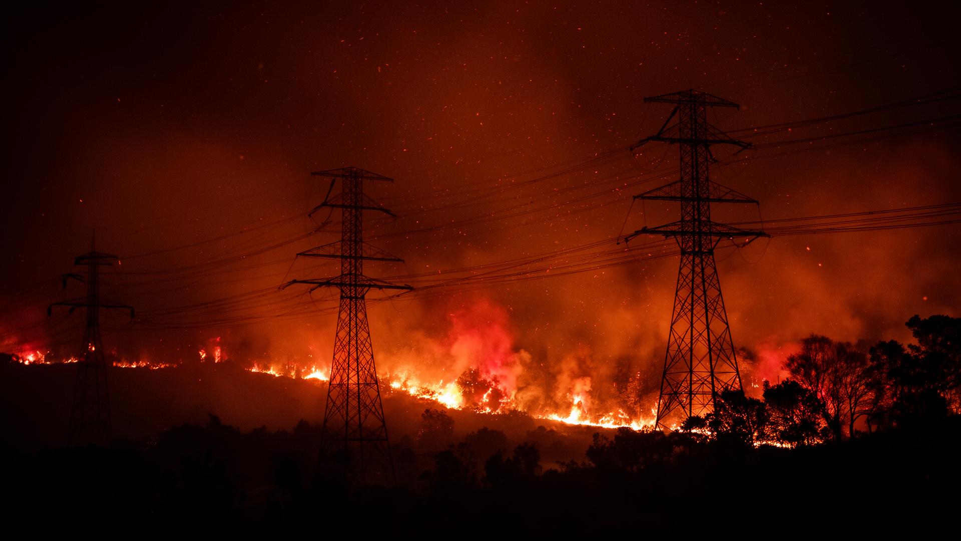 Wildfire burning beneath electrical transmission lines at night